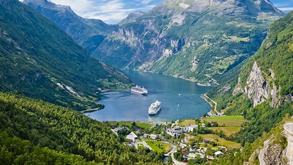Cruise ships sailing through a mountain fjord.